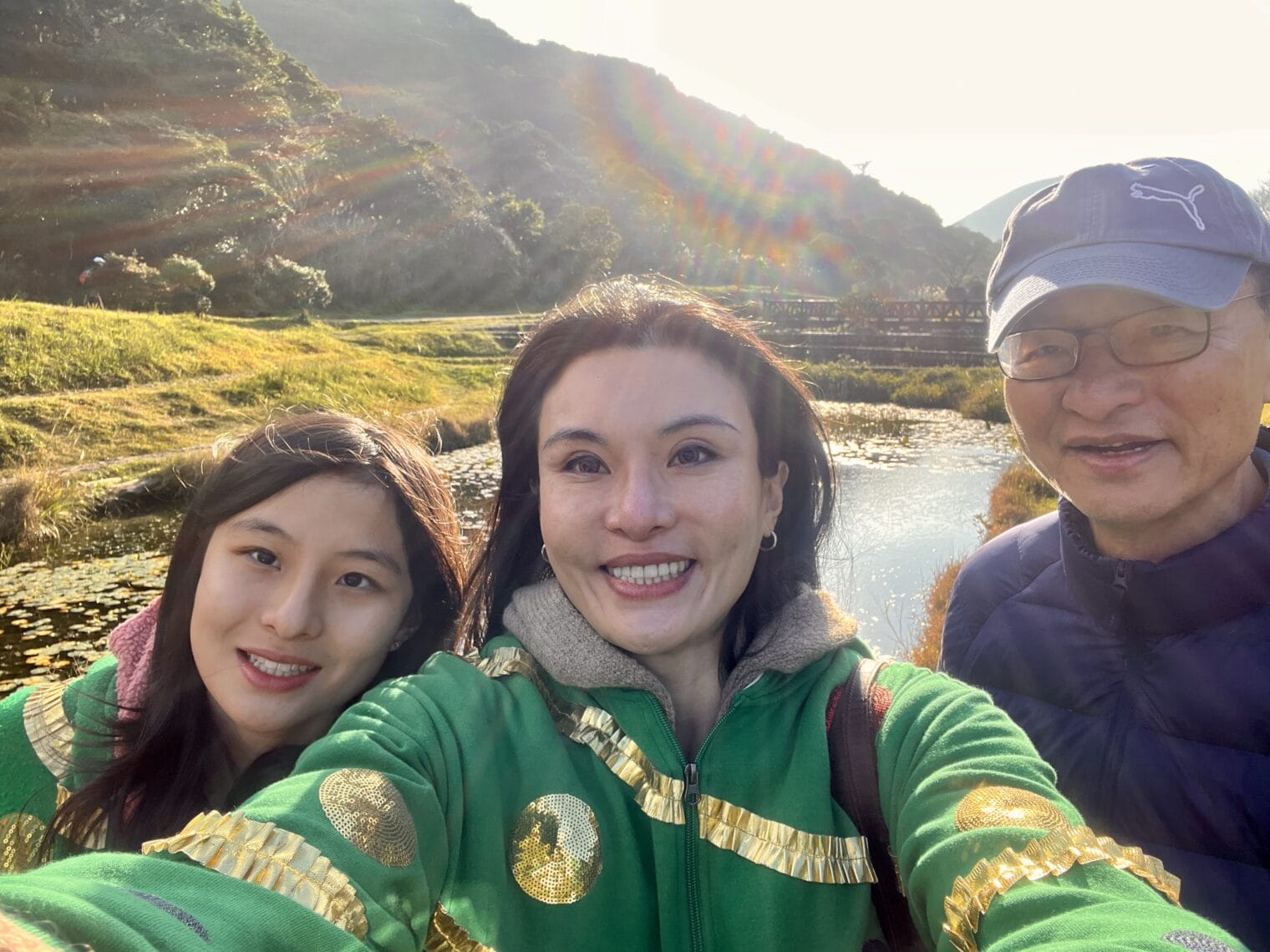 A group of people giving each other a chance to take a selfie in front of a mountain.