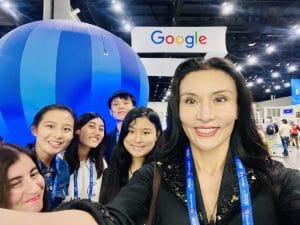 A group of six people pose for a selfie at a tech event, with a large blue structure and a Google sign in the background, celebrating responsible technology and its impact on family wellness.