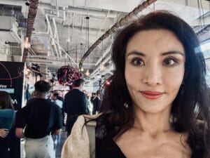 curaJOY CEO takes a selfie at 2025's CTIA Catalyst Wireless for good event where people mingle as active shapers of the experience through technology in the background.