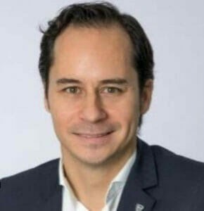 A man in a suit is smiling for the camera during a healthcare equity conference.