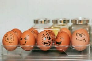 A tray of eggs with faces drawn on them used in parenting behavior therapy for healthcare equity.