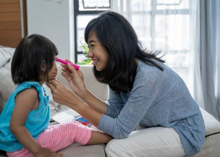 A woman is brushing her daughter's hair.