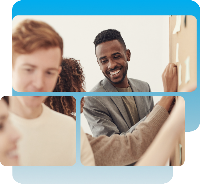 Three people are collaborating in an office, with one man smiling and placing sticky notes on a board while others look on.