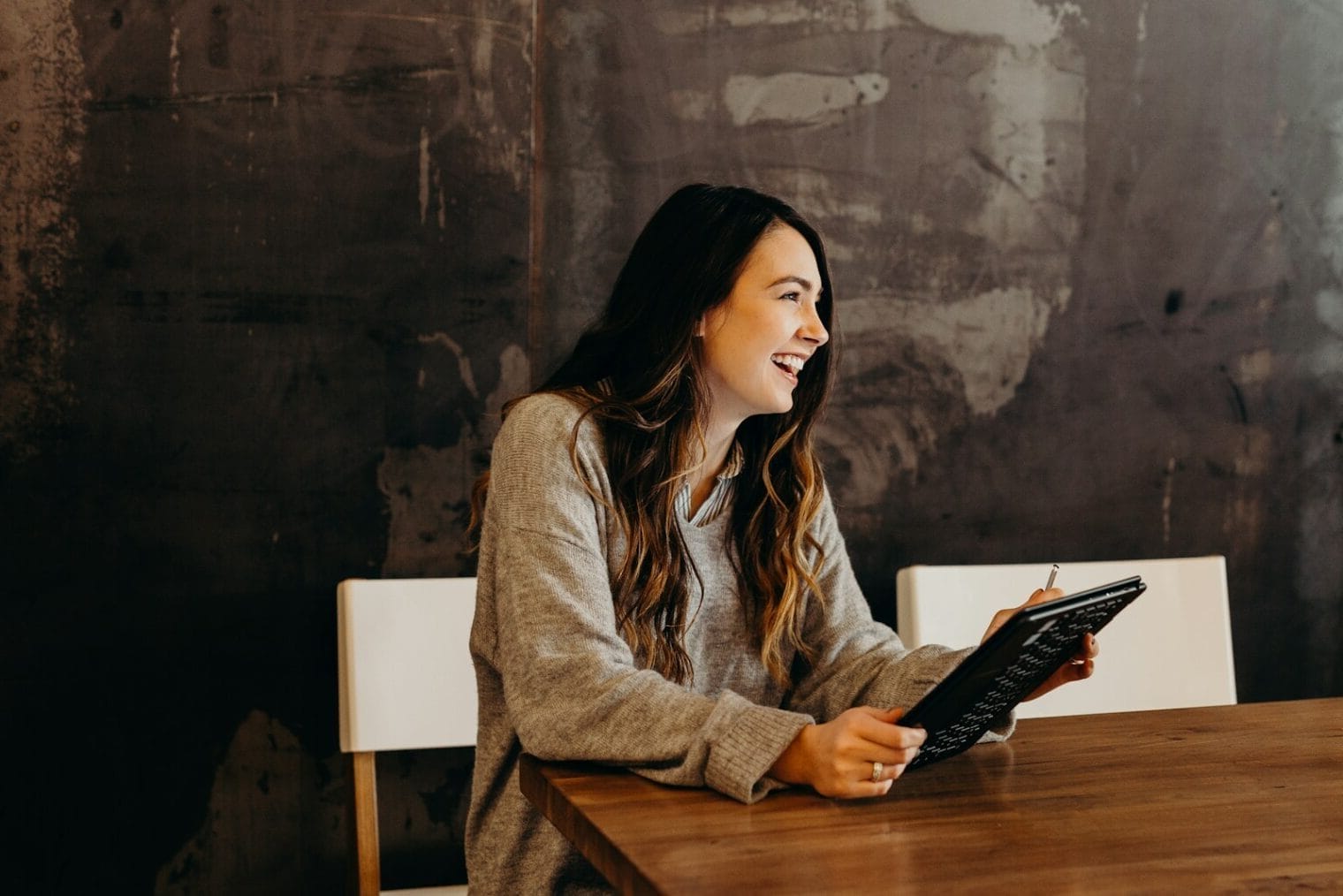 woman sitting around table holding tablet