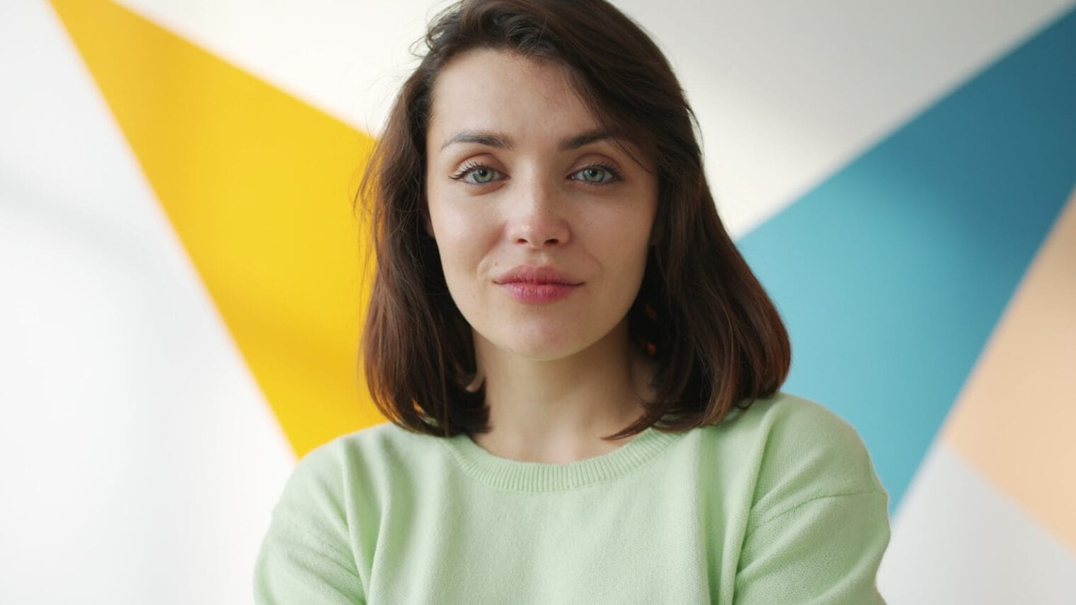 Young woman in a light green sweater smiles gently.