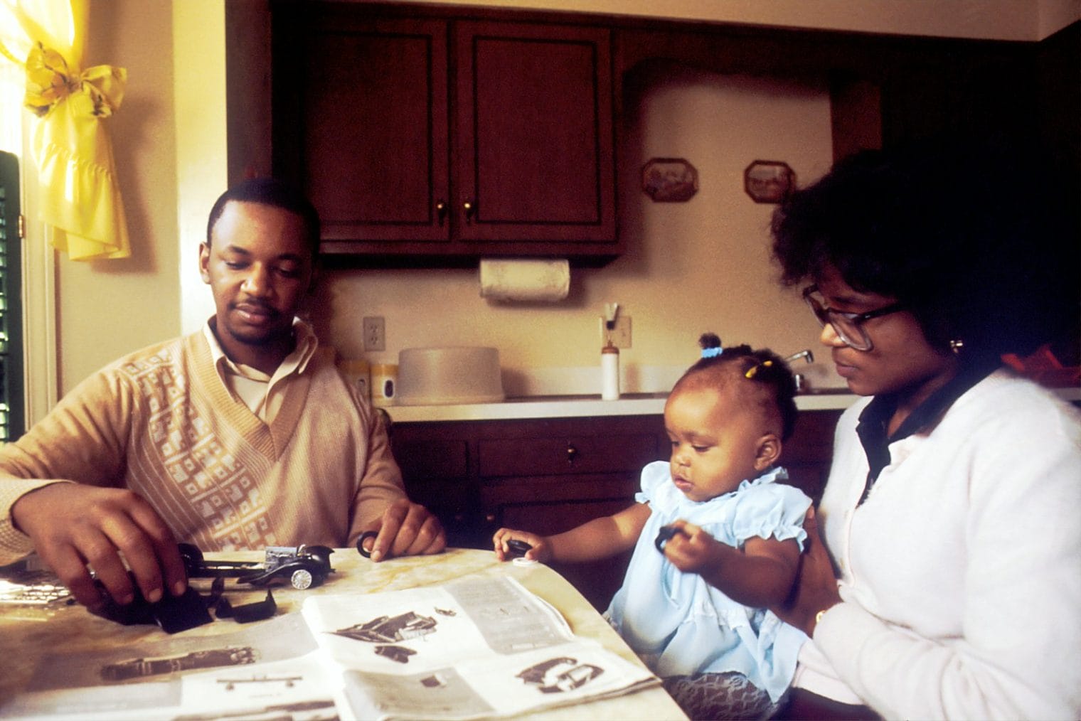 man and woman with child sitting beside table