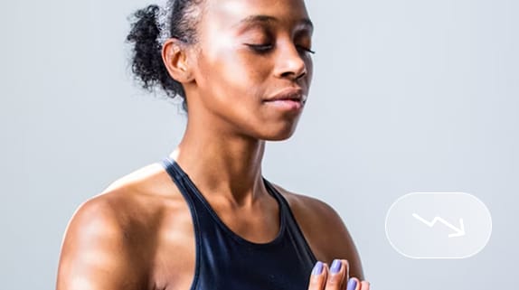 Person in athletic clothing standing with eyes closed and hands together in a prayer position, appearing calm and focused against a plain background—embodying curaJOY’s commitment to youth mental health and family wellness.